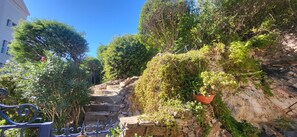 A stone staircase surrounded by lush greenery and a metal railing. - Beau Studio en Centre Ville Avec Terrasse (Sainte-Maxime)