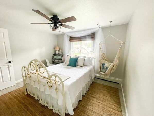 A bedroom with a bed, a hanging chair, a ceiling fan, and a window with curtains. - Family Retreat-Walk to Lake-Cedar Point-Deck/Grill (Vermilion)