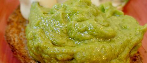 En sandwich med guacamole og en cremet sauce på en rød tallerken.