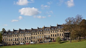 A row of historic townhouses with a grassy park in the foreground.