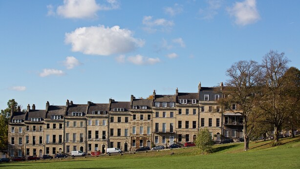 Une rangée de maisons de ville historiques, avec un parc verdoyant en premier plan.