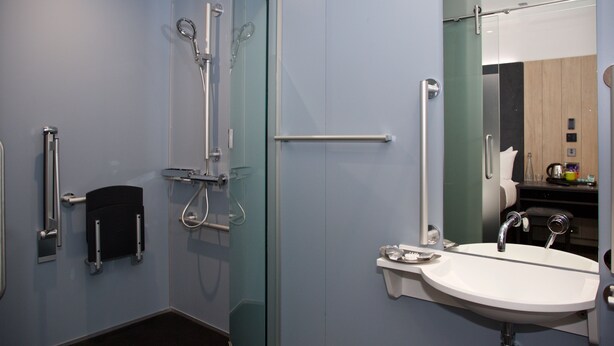 A modern bathroom with a glass shower enclosure, a white sink, and a mirror.
