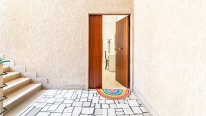 Un passadís amb una porta de fusta, una escala i una catifes amb dibuixos.