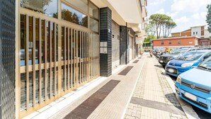 Un edifici modern amb grans finestres, vorera enrajolada i cotxes aparcats.
