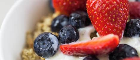 A bowl of yogurt with strawberries and blueberries.
