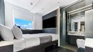A modern bedroom with a bed, a TV, a bathroom with a toilet and sink, and a view of the city. - The Z Hotel Strand (London)