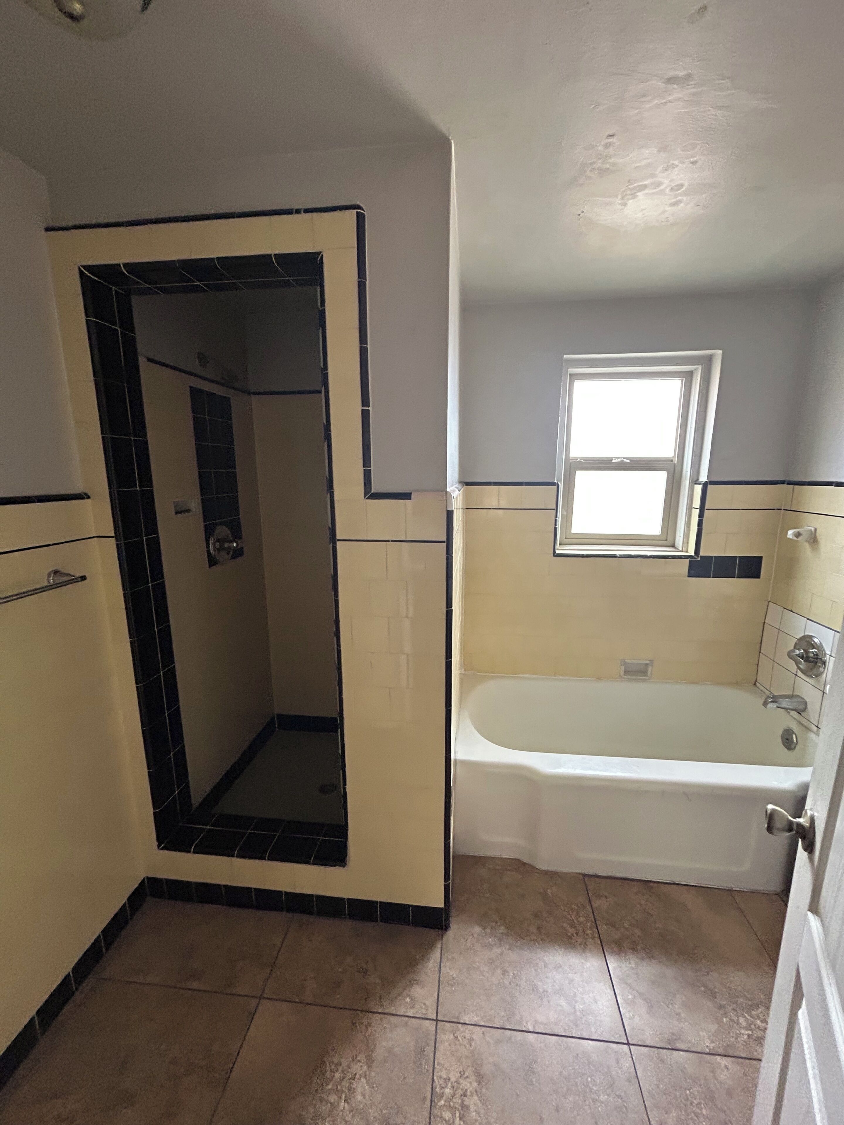 A bathroom with a shower, a bathtub, and a window.
