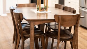 A dining area with a wooden table and chairs, a central decorative piece, and a kitchen in the background. - The Pond View House - quiet country getaway w/ hot tub
 (Leesburg)