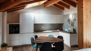 Uma cozinha moderna com armários brancos, uma mesa de jantar de madeira e cadeiras azul-turquesa.