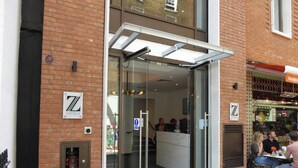 A hotel entrance with a glass door, a fire alarm, and a sign indicating a restaurant on the right. - Z Tottenham Court Road (London)