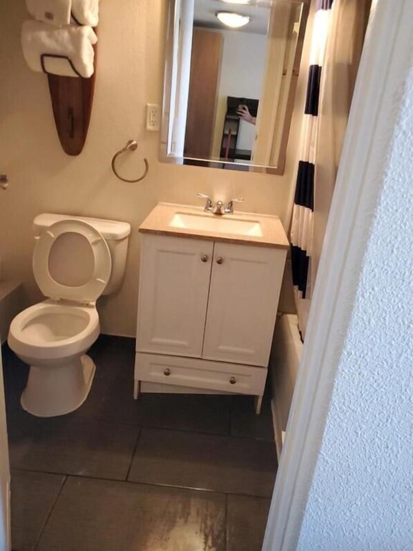 A bathroom with a toilet, a sink, and a mirror. - DESERT HILLS MOTEL (Las Vegas)