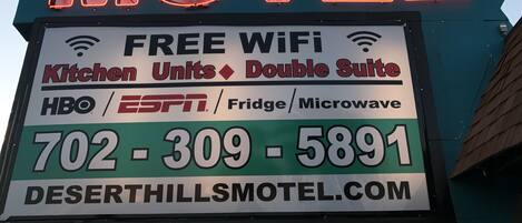 Une enseigne lumineuse au néon du Desert Hills Motel fait la publicité d’un accès Wi-Fi gratuit, de logements avec cuisine, de suites doubles et d’autres commodités, comme les chaînes HBO et ESPN, un réfrigérateur et un four à micro-ondes.