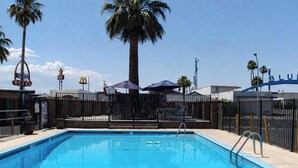 Una piscina con valla, palmeras y un letrero de McDonald's al fondo.
