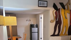 Un espacio habitable compacto con una mesa de comedor, un sofá, una silla, microondas y refrigerador.