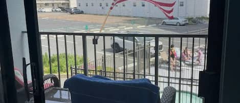 Ein Balkon mit Blick auf einen Parkplatz, ein Gebäude und eine Flagge.