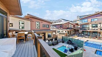 A residential building with a deck, outdoor seating, and a swimming pool.