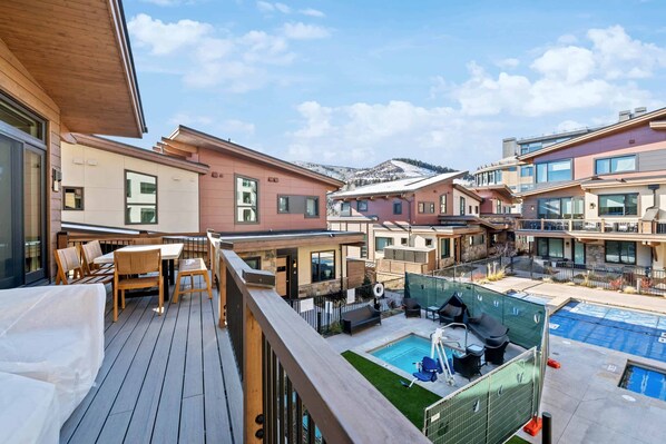 Un edificio residencial con terraza, mobiliario exterior y piscina.
