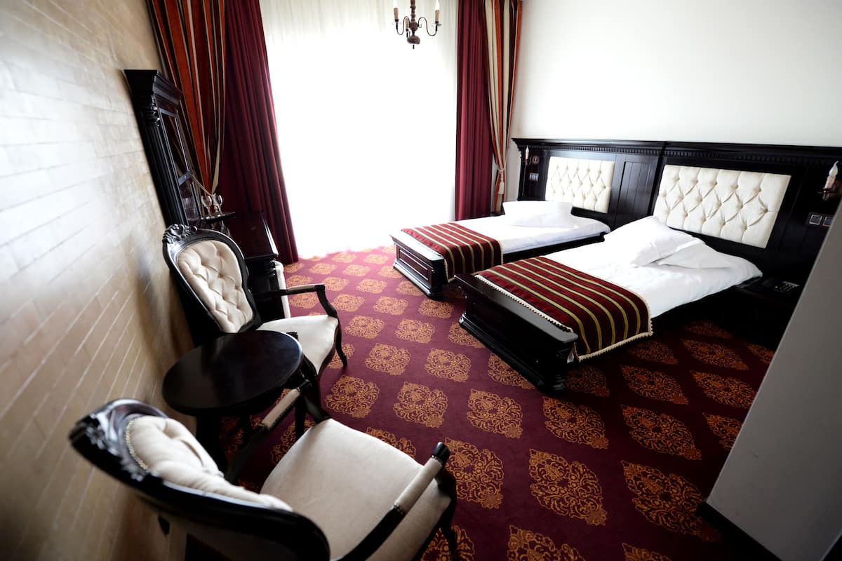 A hotel room with two beds, a sitting area, and a mirror.