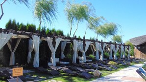 A row of sun loungers under white canopies, a sign indicating a VIP zone, and a pathway leading to a building with a thatched roof. - CASTEL TRANSILVANIA (Baia Mare)