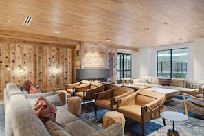 A modern living room with wooden walls, a large TV, and a sofa set. - Frontgate by EWH (Avon)
