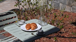 A metal table with a plate of croissants, a cup, and a vase with flowers. - Modern cozy home, pet friendly (Wolcott)