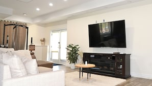 A living room with a sofa, a TV, a fireplace, and a plant. - Modern cozy home, pet friendly (Wolcott)