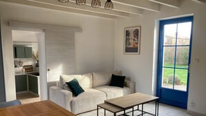 Sala de estar moderna com sofá, mesa de centro e vista para um jardim através de uma porta azul.