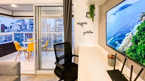 Un espace de bureau moderne doté d’une grande fenêtre, d’un bureau, d’une chaise et d’un grand écran affichant une vue panoramique sur l’océan.