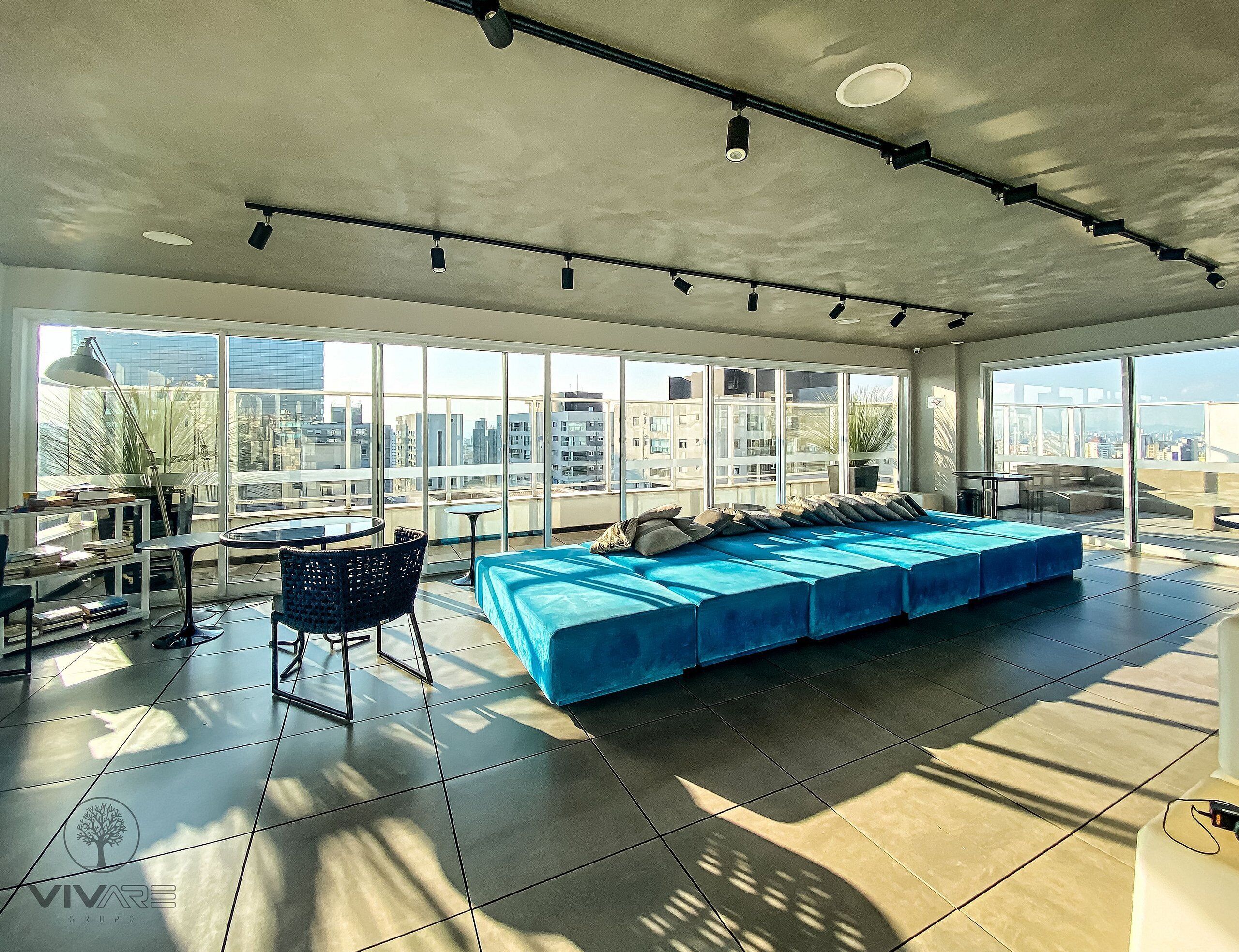 Una habitación amplia con una cama grande, un comedor y grandes ventanales con vistas a la ciudad.