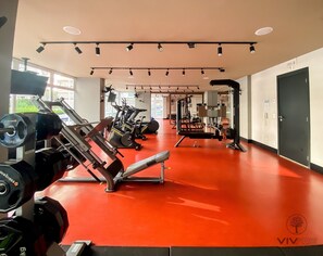 A gym with red flooring, weight machines, and cardio equipment. - Sky Visiom (São Paulo)