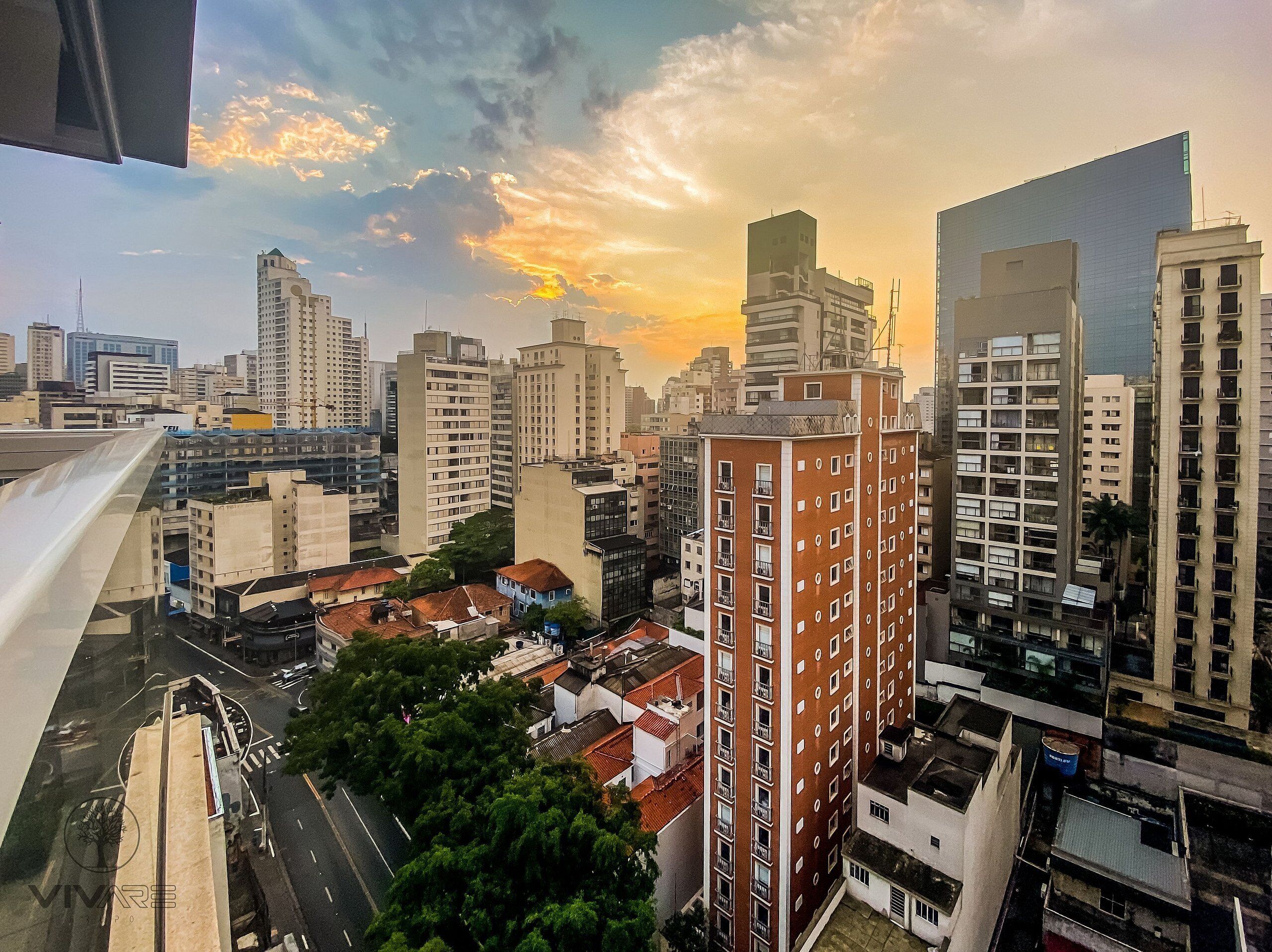 A cityscape with high-rise buildings, a mix of residential and commercial structures, and a clear sky with clouds.