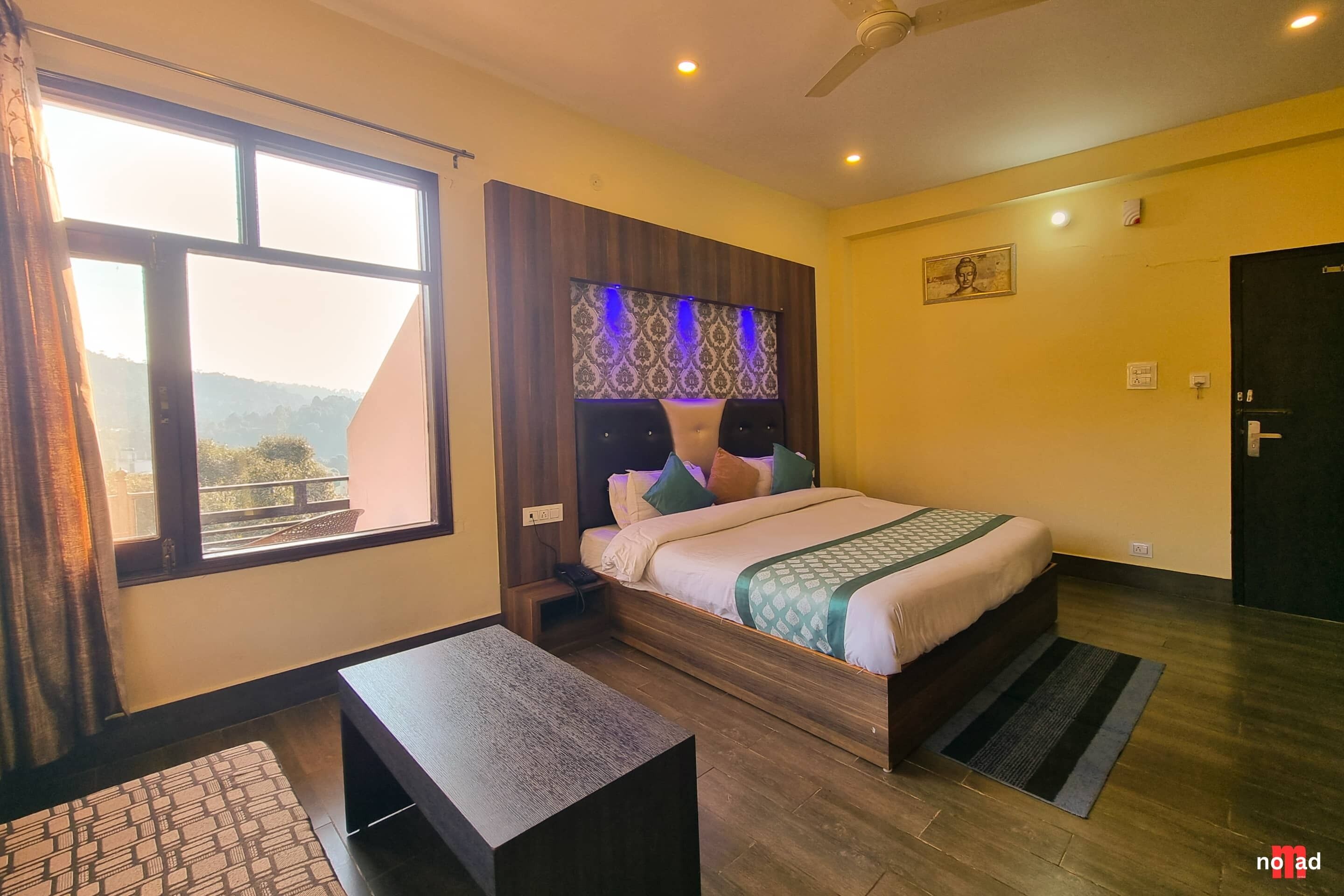 Una habitación de hotel con cama, mesita de noche y ventana con cortinas.