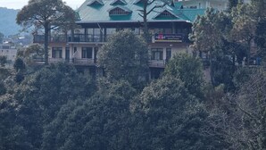 A building with a green roof and multiple balconies, surrounded by trees. - Nature Nest By Nomad Hotels (Dalhousie)