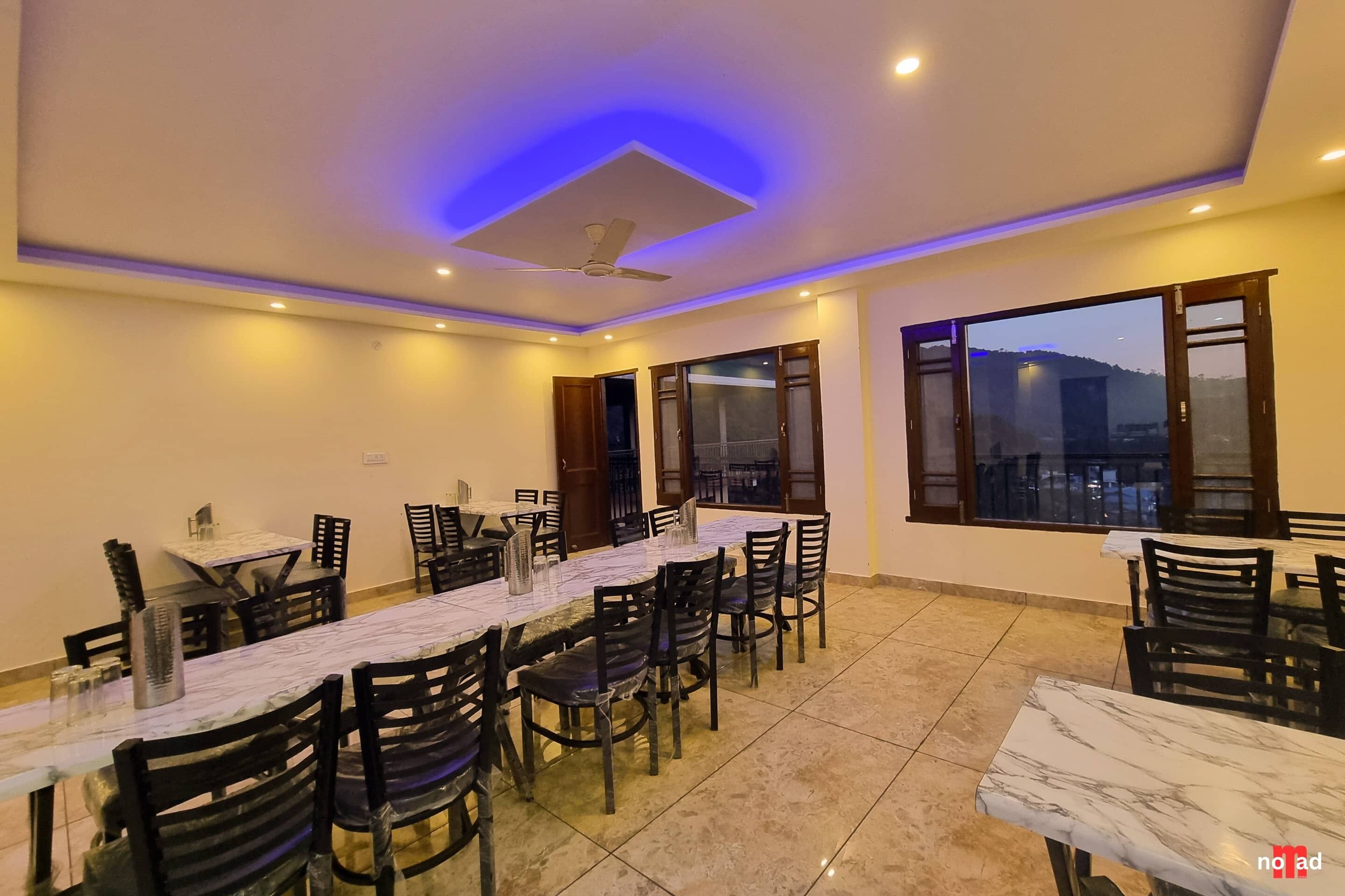 A dining area with multiple tables and chairs, a ceiling fan, and large windows with a view.
