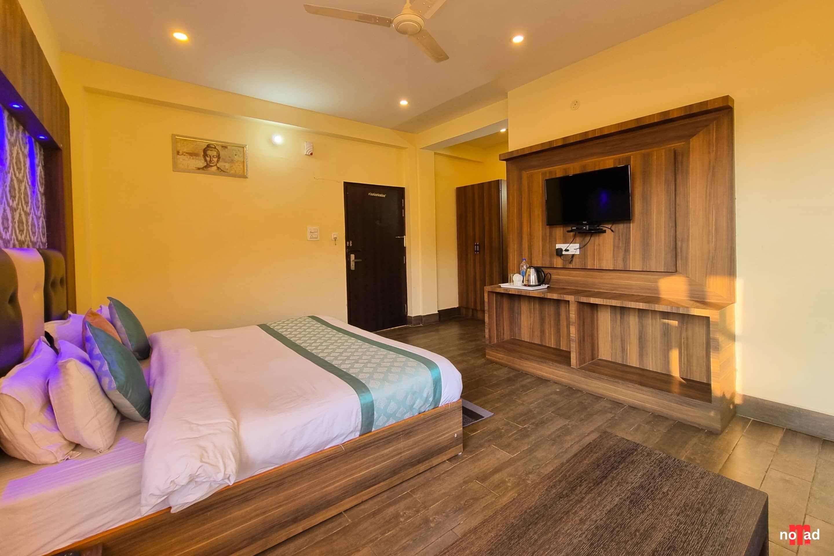 Habitación de hotel con cama, piso de madera, televisor montado en un panel de madera y una puerta con la etiqueta 'PARKING'.