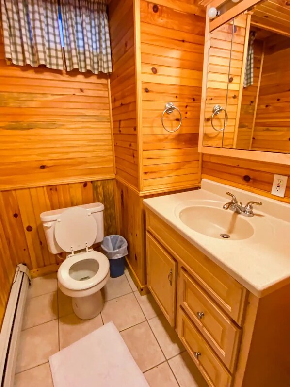 Une salle de bain en bois avec des toilettes, un lavabo et un miroir.