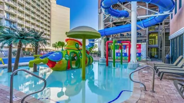 Ein Poolbereich mit Wasserrutsche und einer bunten Spielanlage.