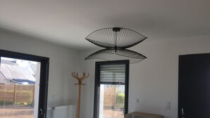 A room with a large window, a wooden coat rack, a ceiling fan, and a cabinet.