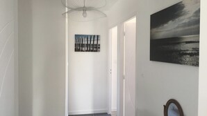 A hallway with a modern pendant light, a beach-themed painting, and a mirror on the wall.