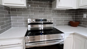 A kitchen with white cabinets, a stainless steel range, and a black oven.