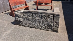 Un patio con dos bancos de madera y una pared de piedra.