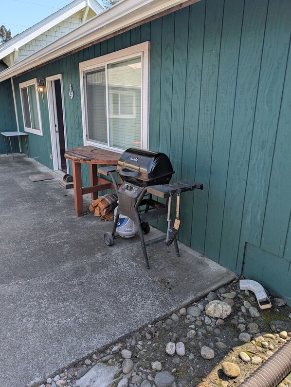 Un patio con una parrilla, una mesa y una silla.