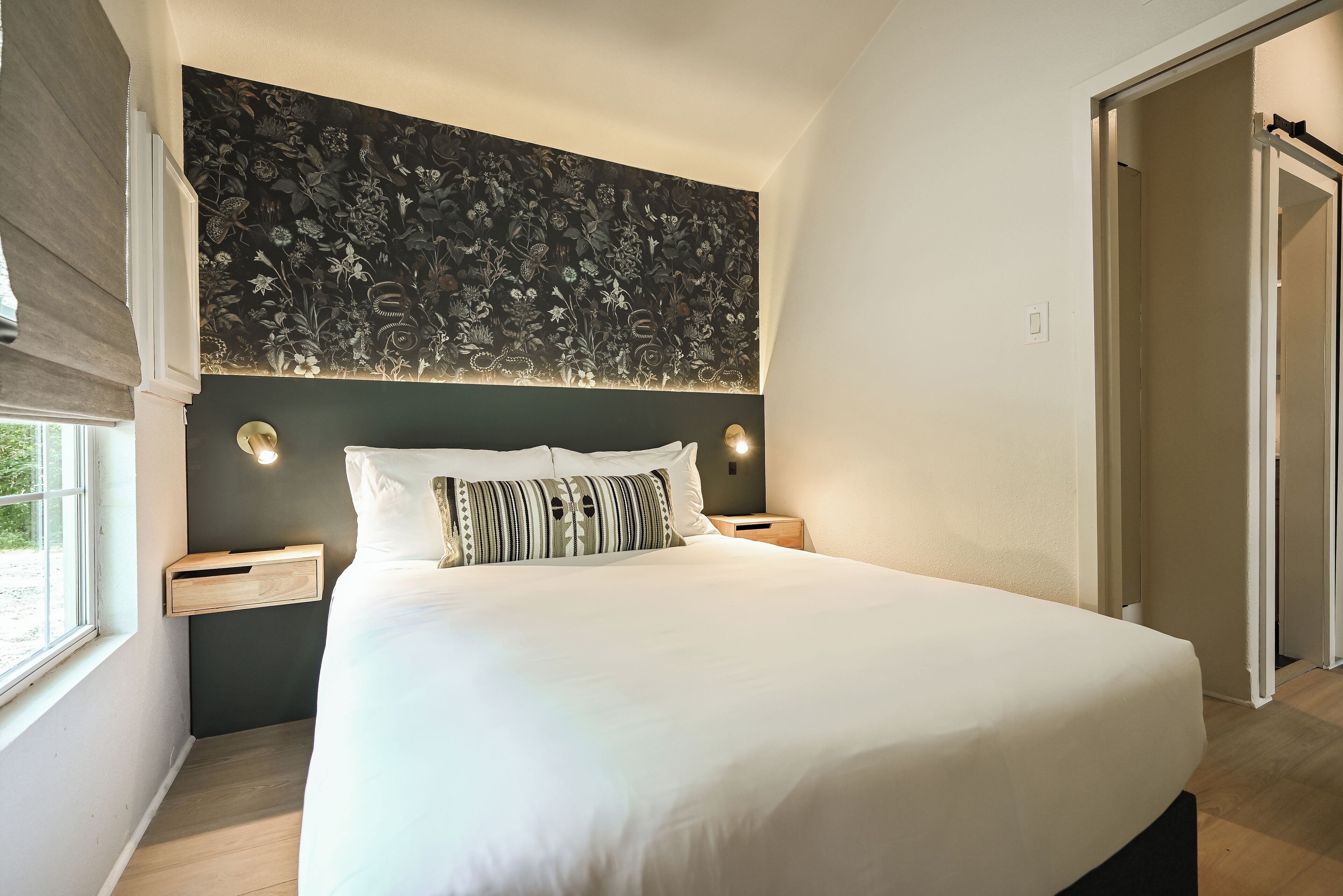 A bedroom with a large bed, dark headboard, and bedside tables with lamps.
