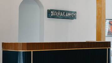 A reception desk with a dark finish, a woven light fixture above, and a sign with text.