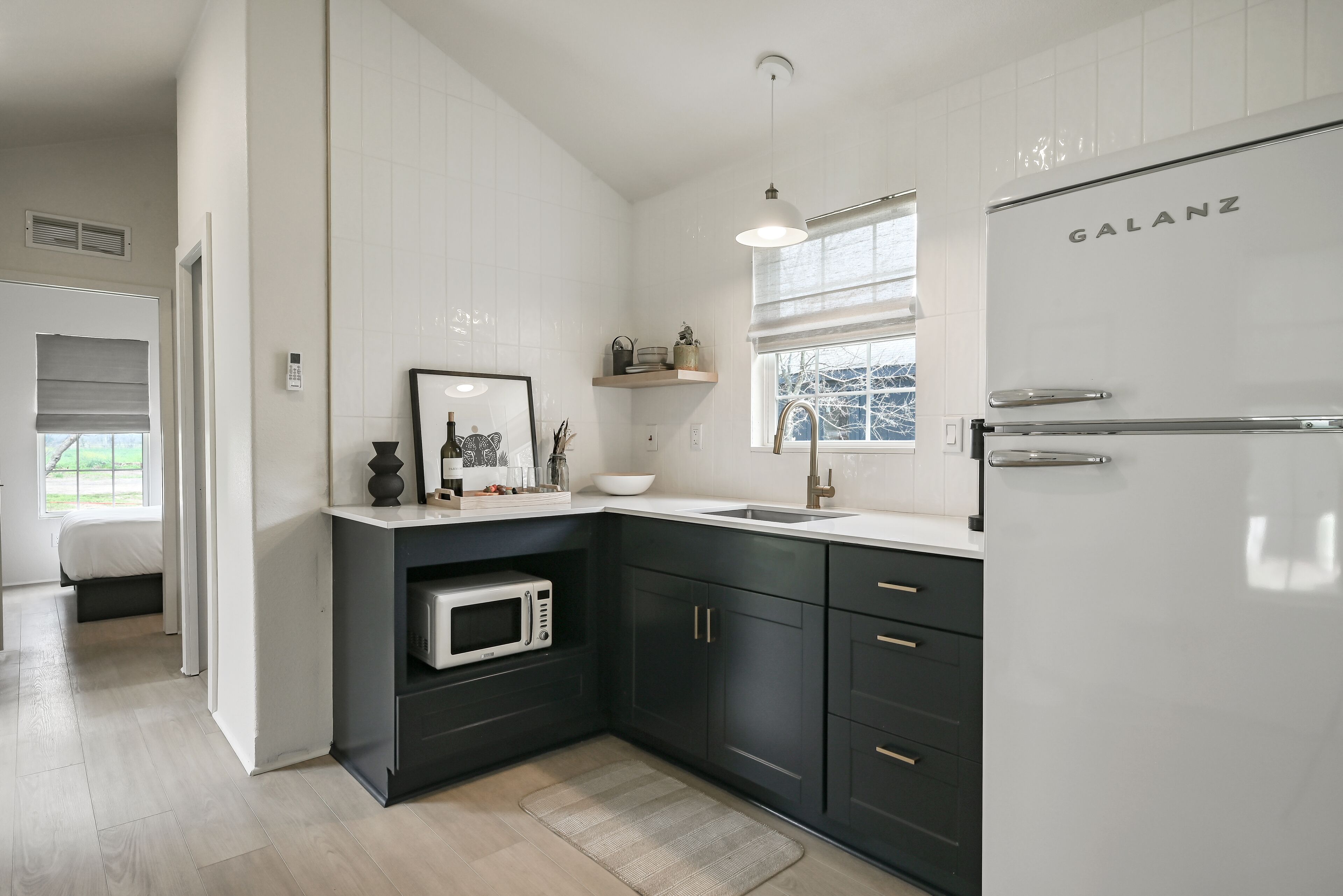 A modern kitchen with dark cabinets, a white refrigerator, and a microwave.