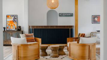 Un vestíbulo moderno con muebles de madera, una mesa central y una lámpara colgante.