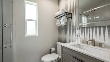 Un baño con inodoro, toallero, lavabo y espejo.