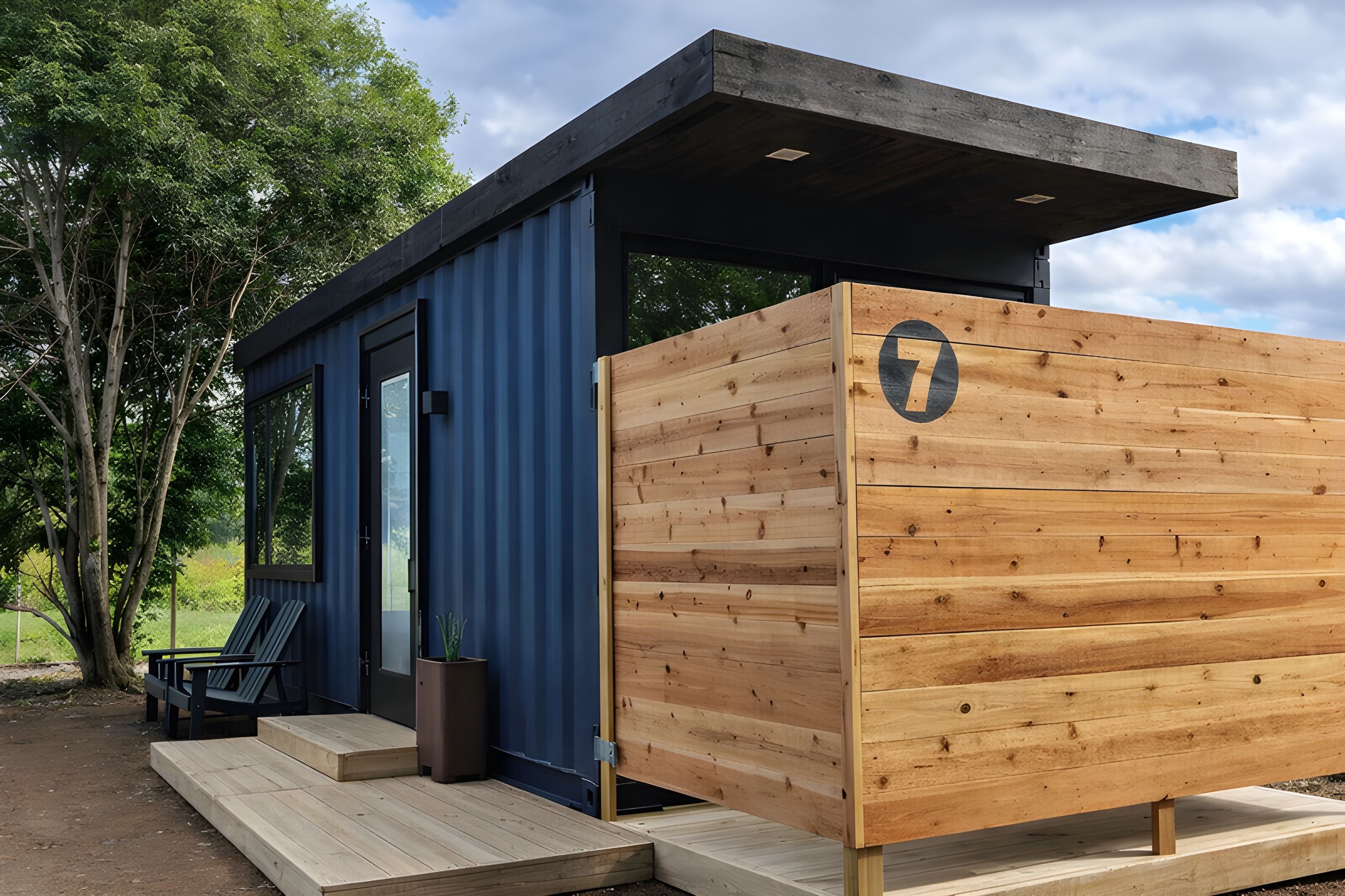 A modern cabin with a wooden exterior, a glass door, and a small porch with seating.