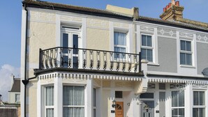 A two-story house with a balcony, a front door, and a number '47' on the wall. - 6 bedroom accommodation in Clacton on Sea (Clacton on Sea)
