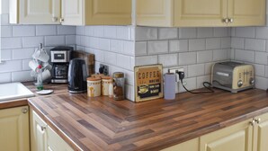 A kitchen with wooden countertops, white cabinets, a coffee maker, a toaster, and a sign that says "Coffee Break Daily." - 6 bedroom accommodation in Clacton on Sea (Clacton on Sea)